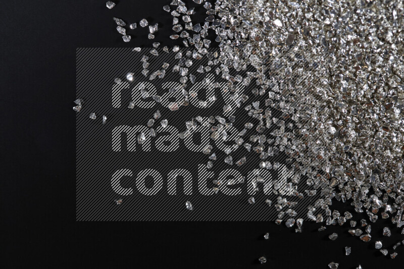 قطع زجاجية فضية لامعة متناثرة على خلفية سوداء