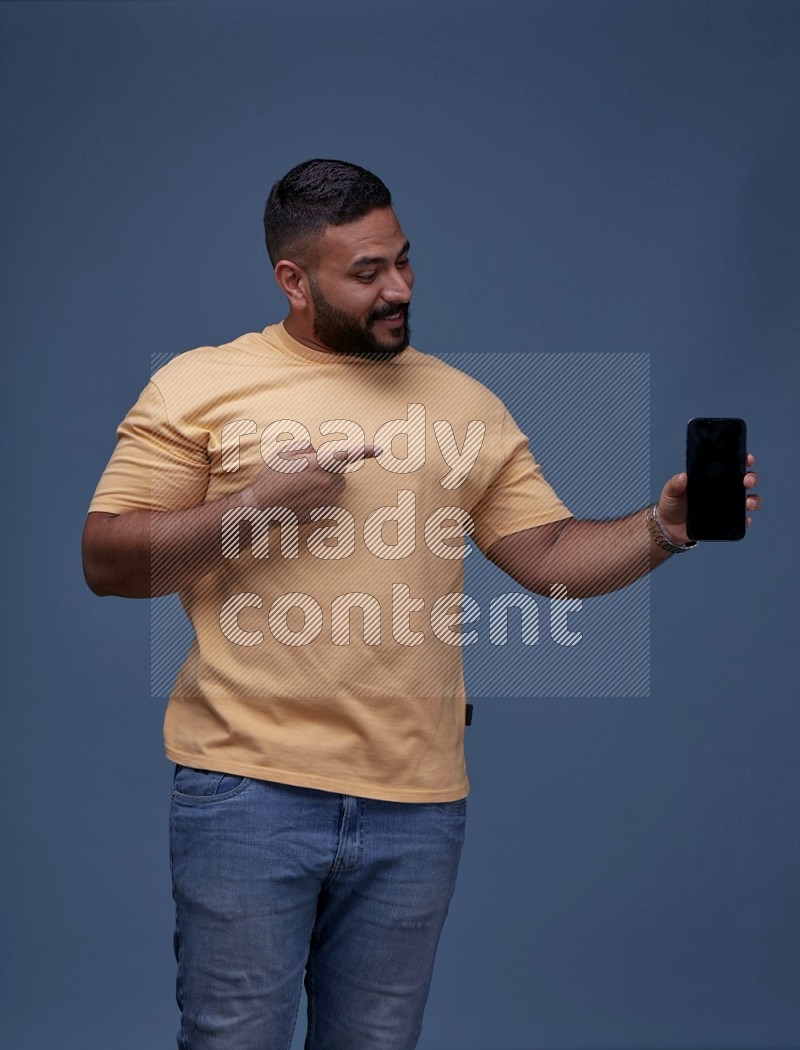 A man Showing His Smart Phone on Blue Background wearing Orange T-shirt