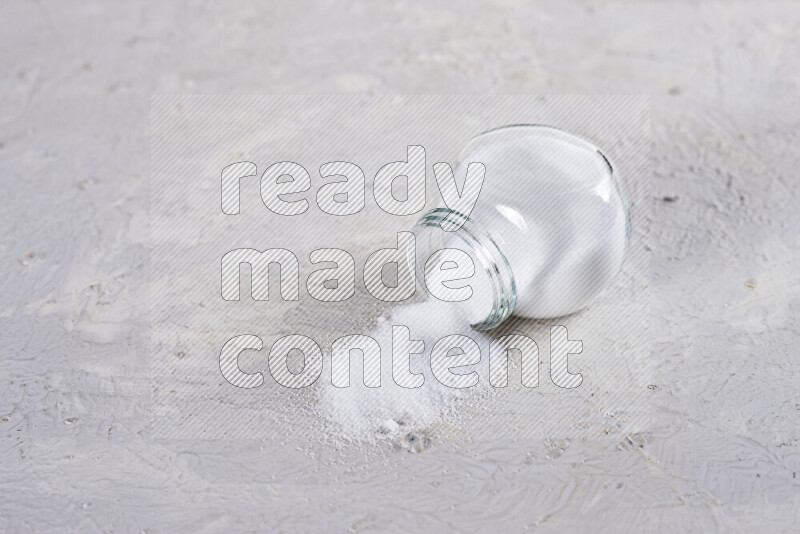 A glass jar full of fine table salt on white background