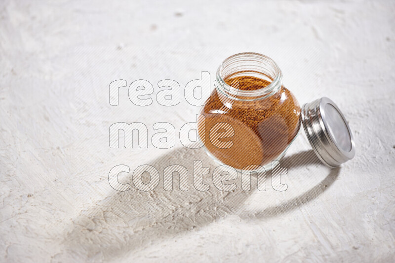 A glass jar full of ground paprika powder on white background