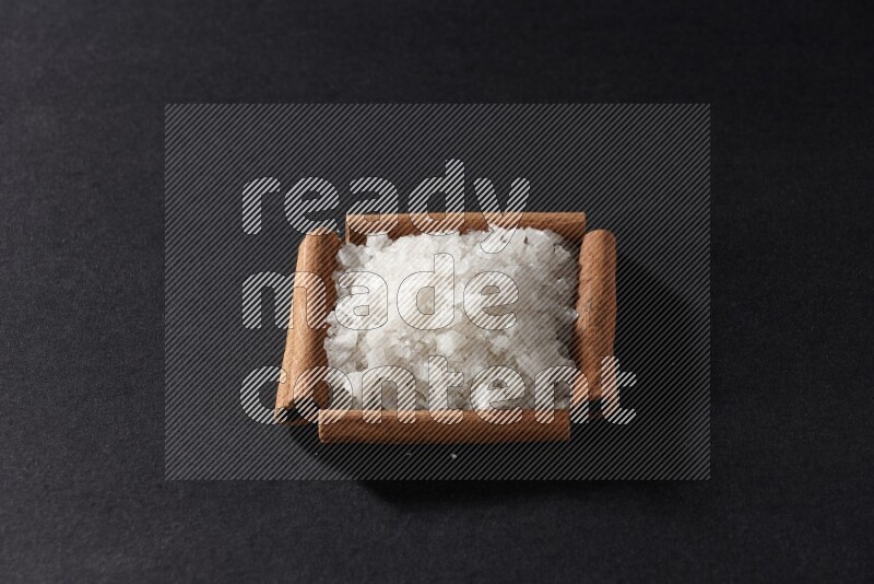 A single square of cinnamon sticks full of salt on black flooring