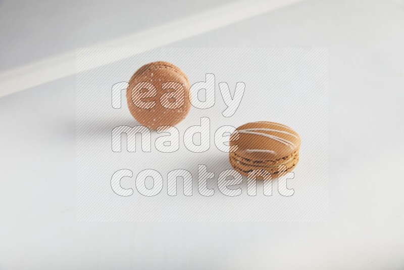45º Shot of of two assorted Brown Irish Cream, and Brown Hazelnuts macarons on white background