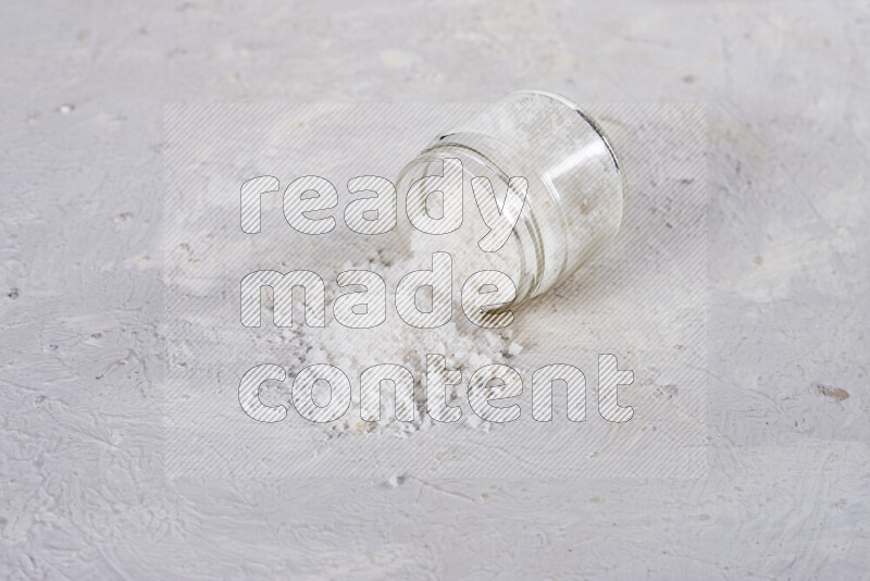 A glass jar full of coarse sea salt crystals on white background