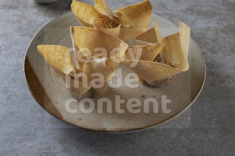 wonton cups with soy sauce ramkin on multi colored pottery on grey textured counter top
