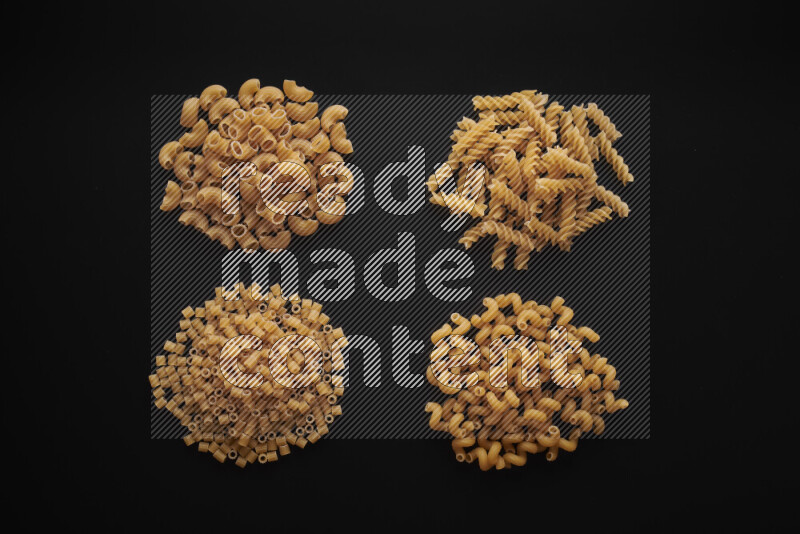 Different pasta types in bunches on black background