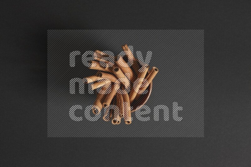 Cinnamon Sticks in a wooden bowl on black background