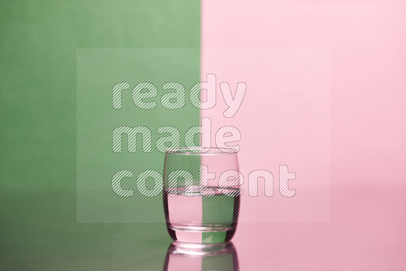 The image features a clear glassware filled with water, set against green and rose background