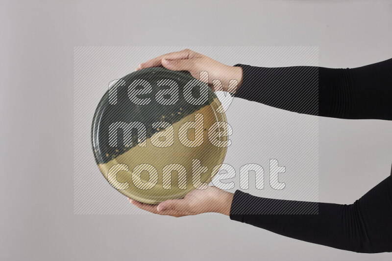 A woman in black abaya holding different pottery essentials in different positions