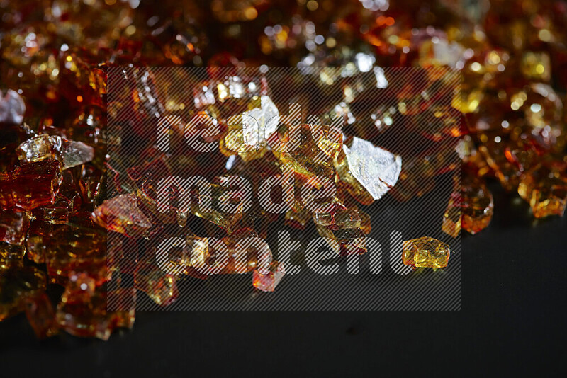 Transparent orange fragments of glass scattered on a black background