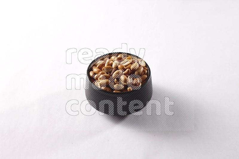 Peanuts in a black pottery bowl on white background
