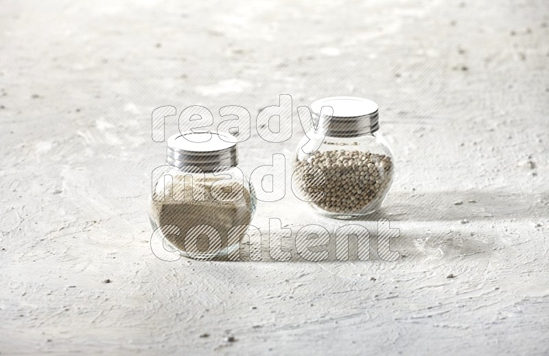 2 Herbal Glass jar full of white pepper beads and powder on textured white flooring