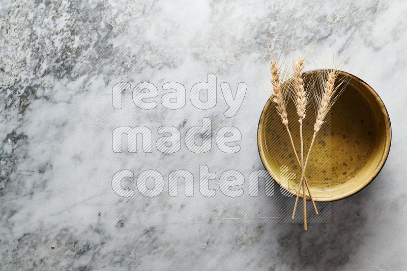 Wheat stalks on Multicolored Pottery Oven Plate on grey marble flooring, Top view