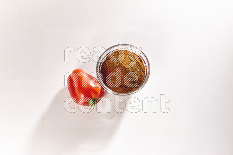 A glass bowl full of ground paprika powder on white background