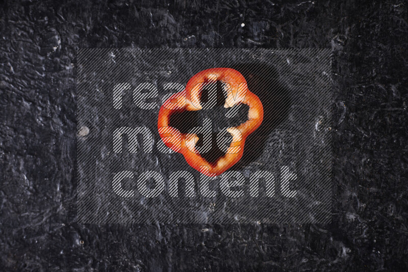 Red bell pepper slices on black background