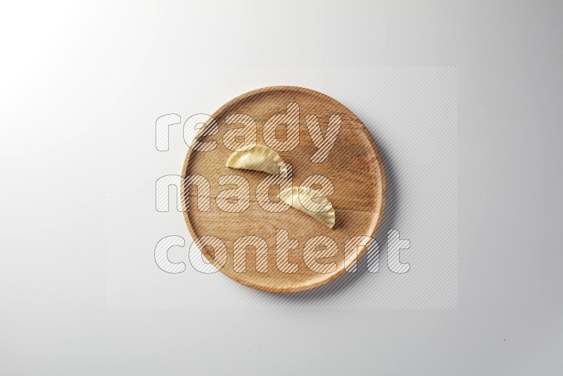 Two Sambosas on a wooden round plate on a white background