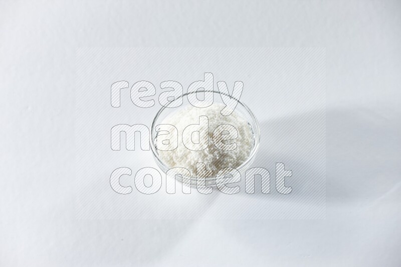 A glass bowl full of desiccated coconut on a white background in different angles