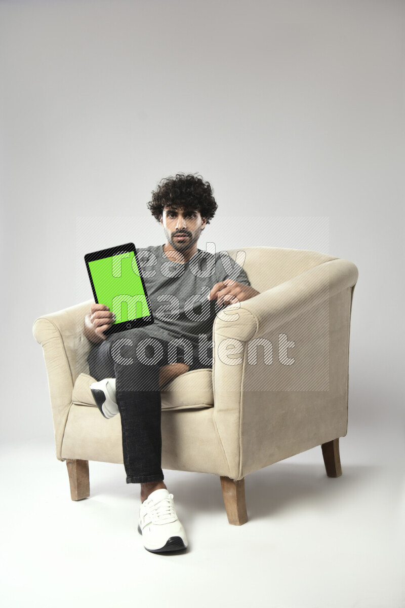 A man wearing casual sitting on a chair showing a tablet screen on white background