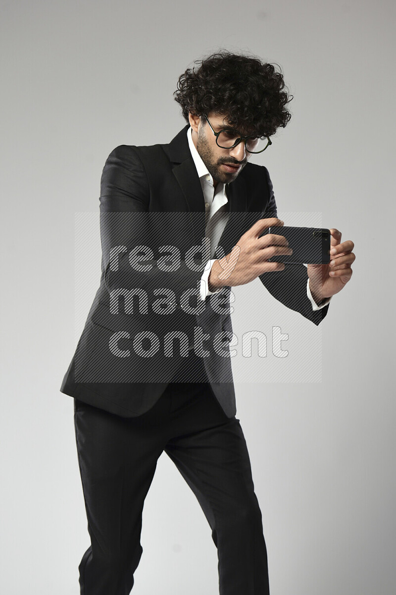 A man wearing formal standing and shooting with his phone on white background