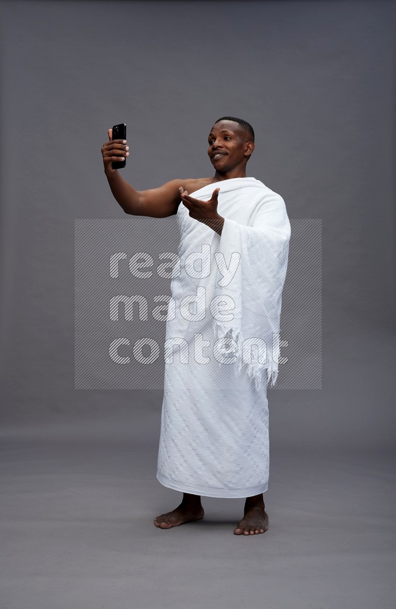 A man wearing Ehram Standing taking selfie on gray background