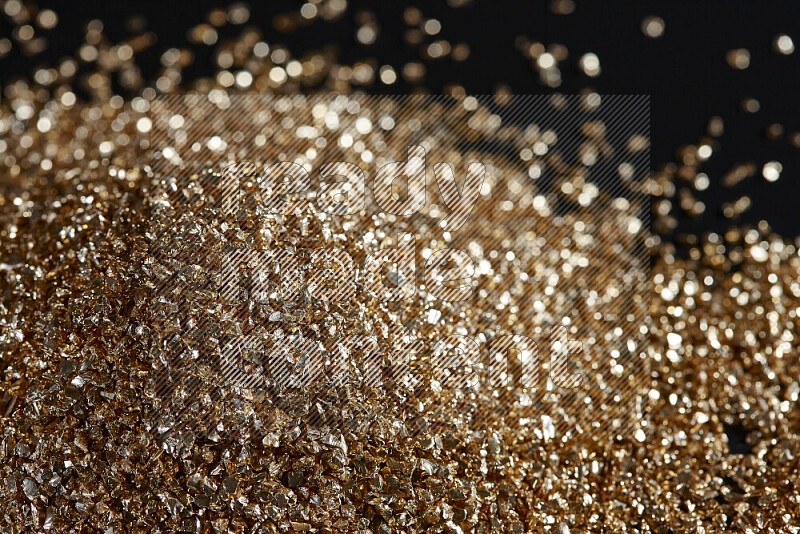 Gold shimmering fragments of glass scattered on a black background