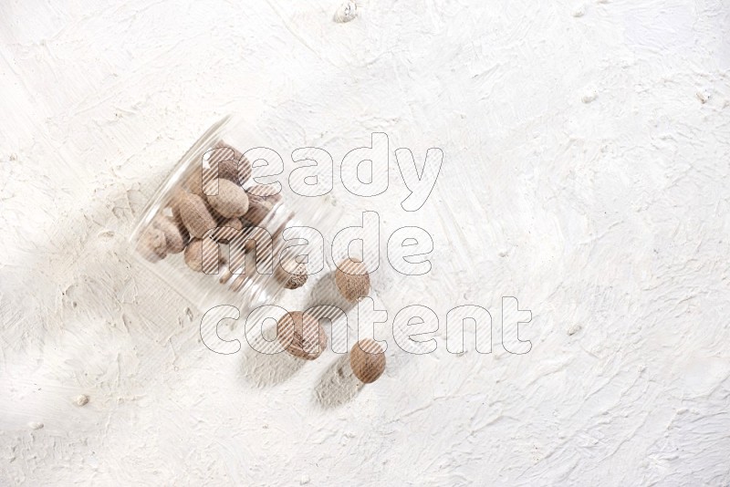 A glass jar full of nutmeg flipped and the seeds came out on a textured white flooring in different angles