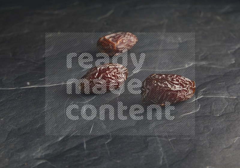 three madjoul dates on a black textured background