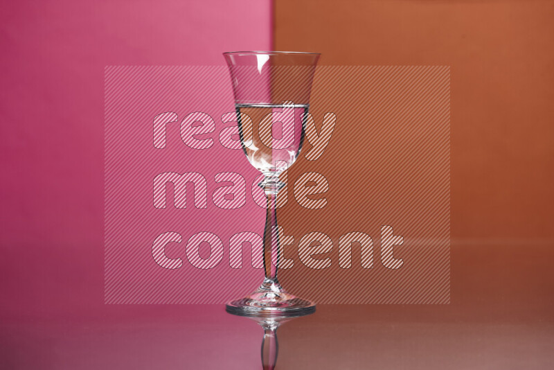 The image features a clear glassware filled with water, set against pink and dark orange background