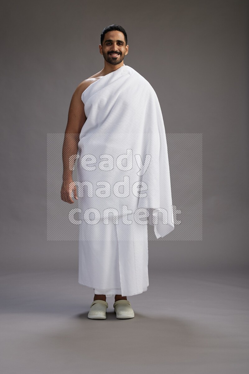 A man wearing Ehram Standing Interacting with the camera on gray background