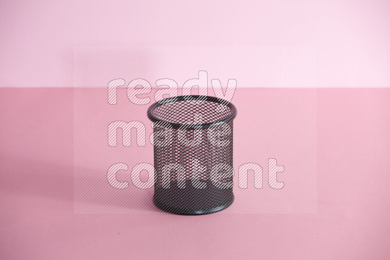 Pens, pencils and other different school supplies in a metal pen holder on rose background