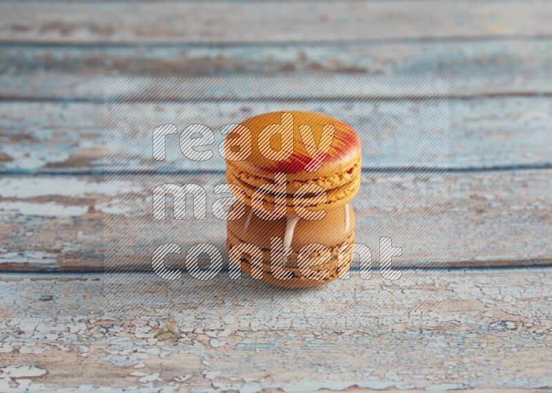 45º Shot of of two assorted Brown Irish Cream, and Orange Exotic macarons on light blue background
