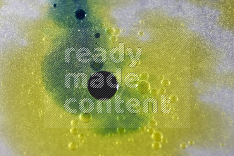 Close-ups of abstract yellow, blue and green watercolor drops on oil Surface on white background