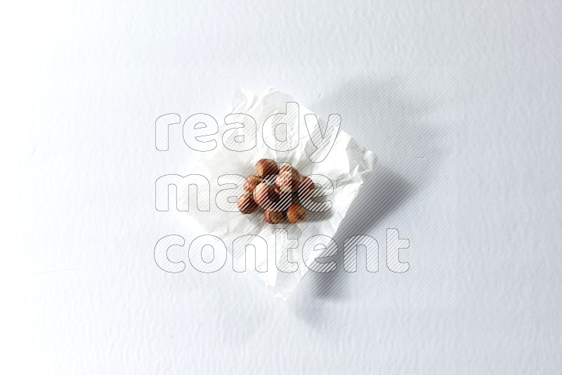 Hazelnuts on a crumpled piece of paper on a white background in different angles