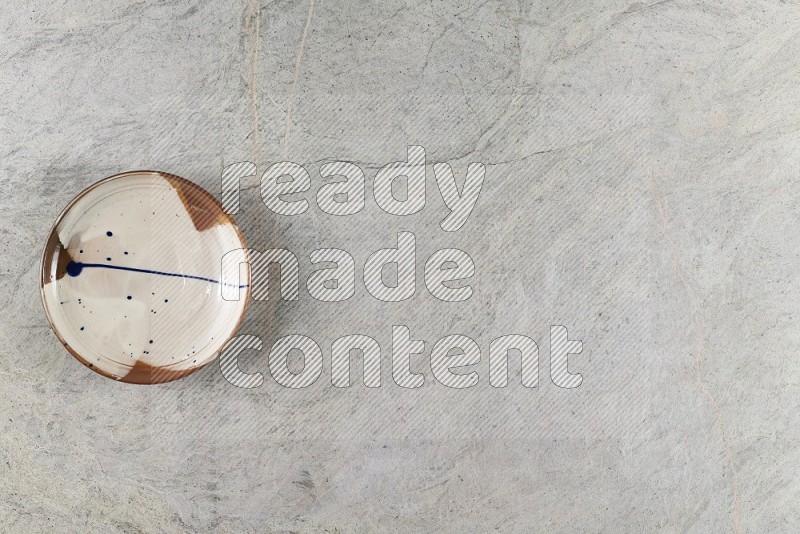 Top View Shot Of A Multicolored Pottery Plate On Grey Marble Flooring