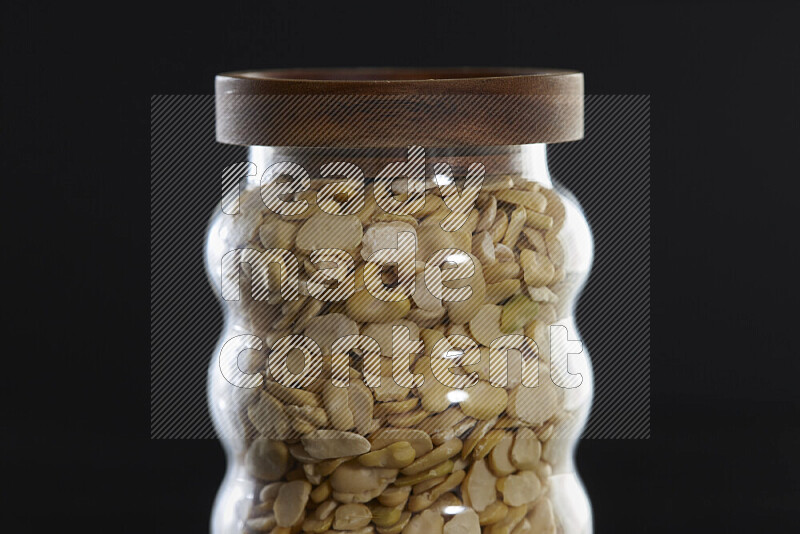 Crushed beans in a glass jar on black background