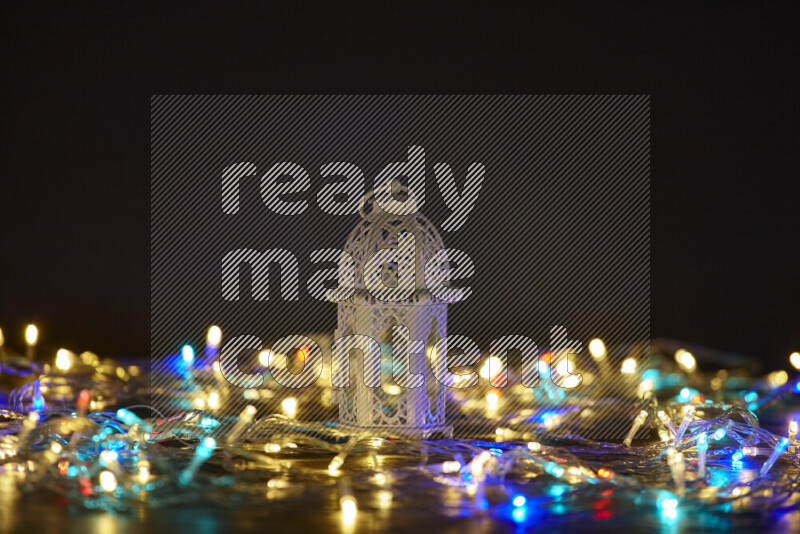 A traditional ramadan lantern surrounded by glowing fairy lights in a dark setup