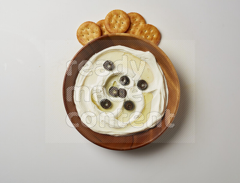 Lebnah garnished with sliced olives in a wooden plate on a white background