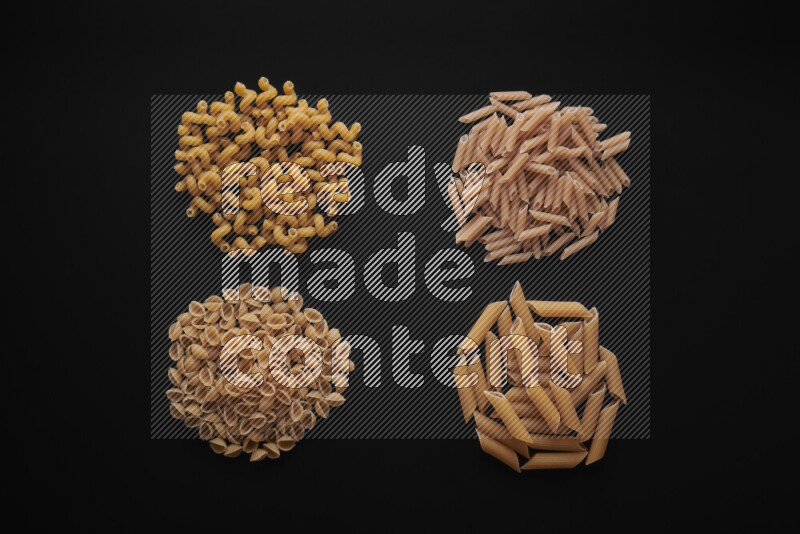 Different pasta types in bunches on black background