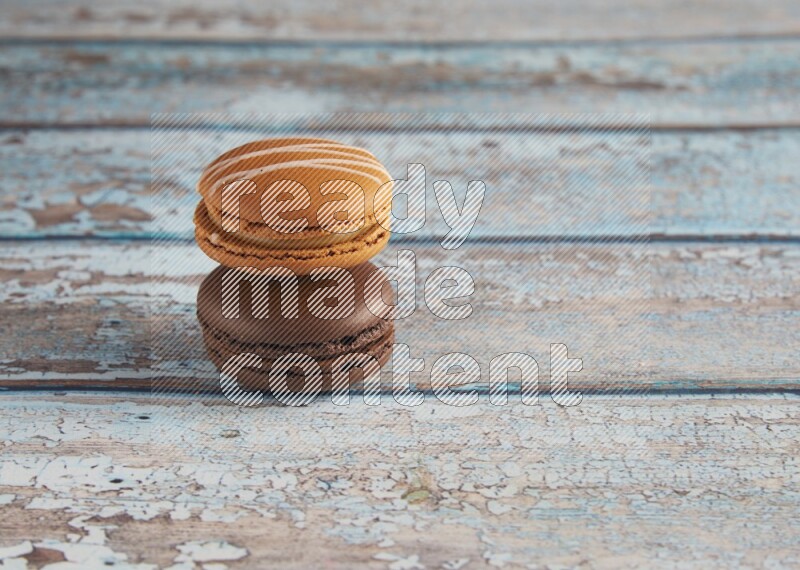 45º Shot of of two assorted Brown Irish Cream, and Brown Dark Chocolate macarons on light blue background