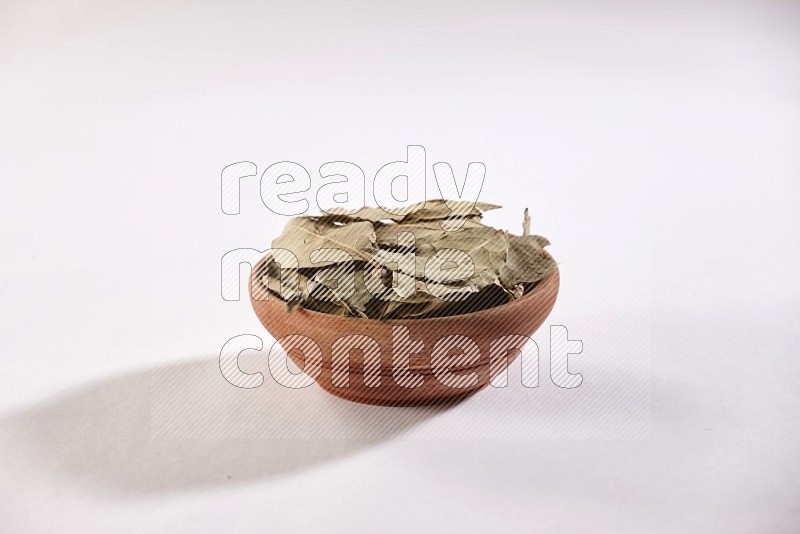 A wooden bowl filled with laurel bay on white flooring in different angles