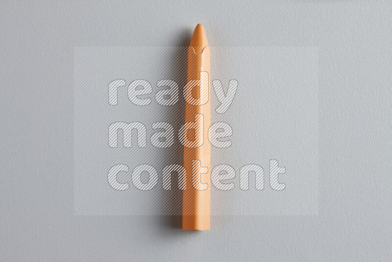 A close-up showing a single wax crayon on grey background