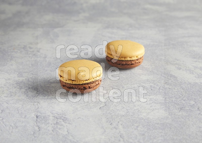 45º Shot of two Yellow and Brown Chai Latte macarons r on white  marble background