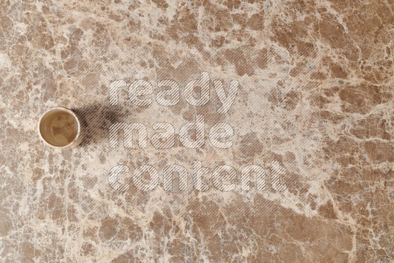 A pottery cup on beige marble background