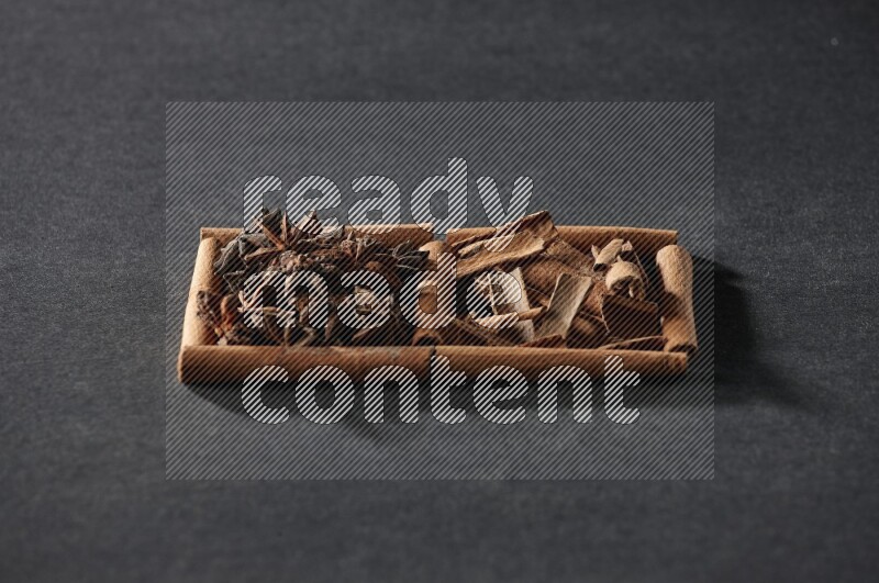 مربعان من أعواد القرفة ممتلئان باليانسون النجمي وقطع من القرفة علي خلفية سوداء