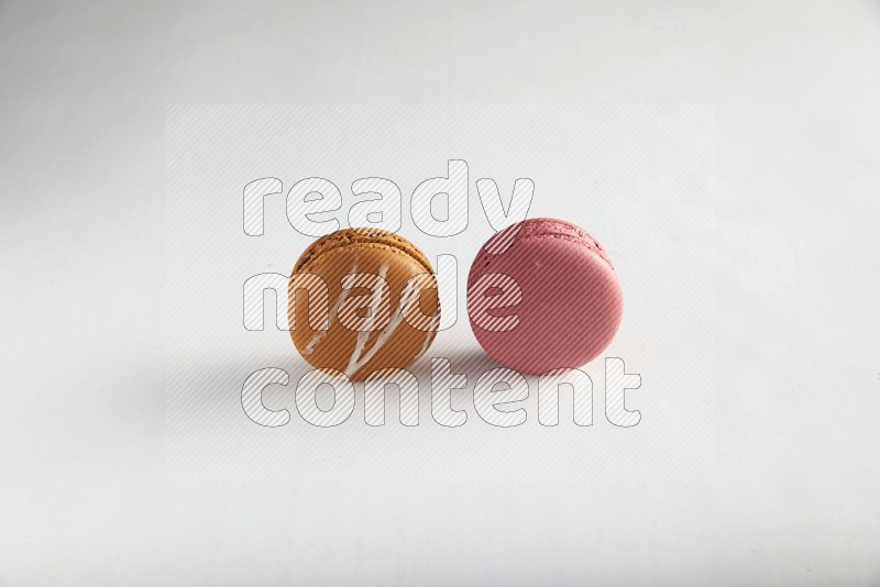 45º Shot of of two assorted Brown Irish Cream, and Pink Raspberry macarons on white background