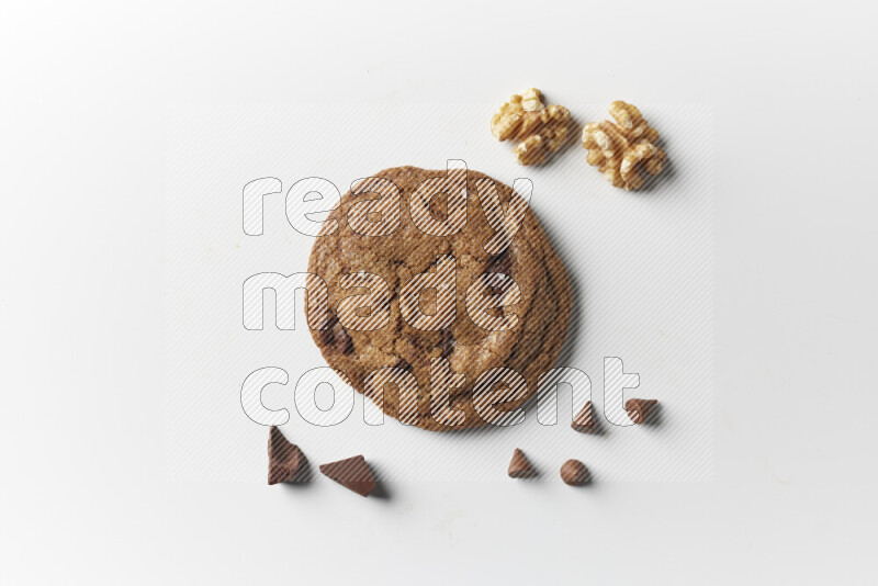 A single chocolate chips cookie with chocolate and walnuts beside it on a white background