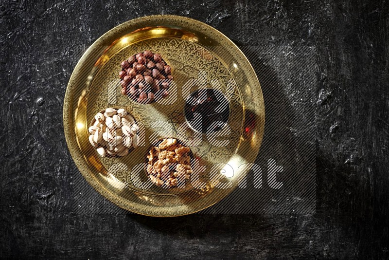 Nuts in metal bowls with tamarind on a tray in dark setup