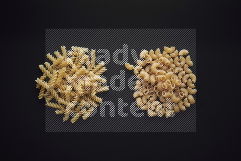 Different pasta types in bunches on black background