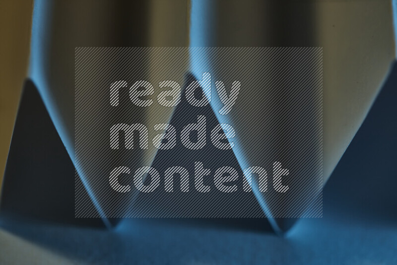 صورة مجردة مقربة تظهر طيات ورقية هندسية حادة بتدرجات اللون الأزرق مع درجات لونية دافئة