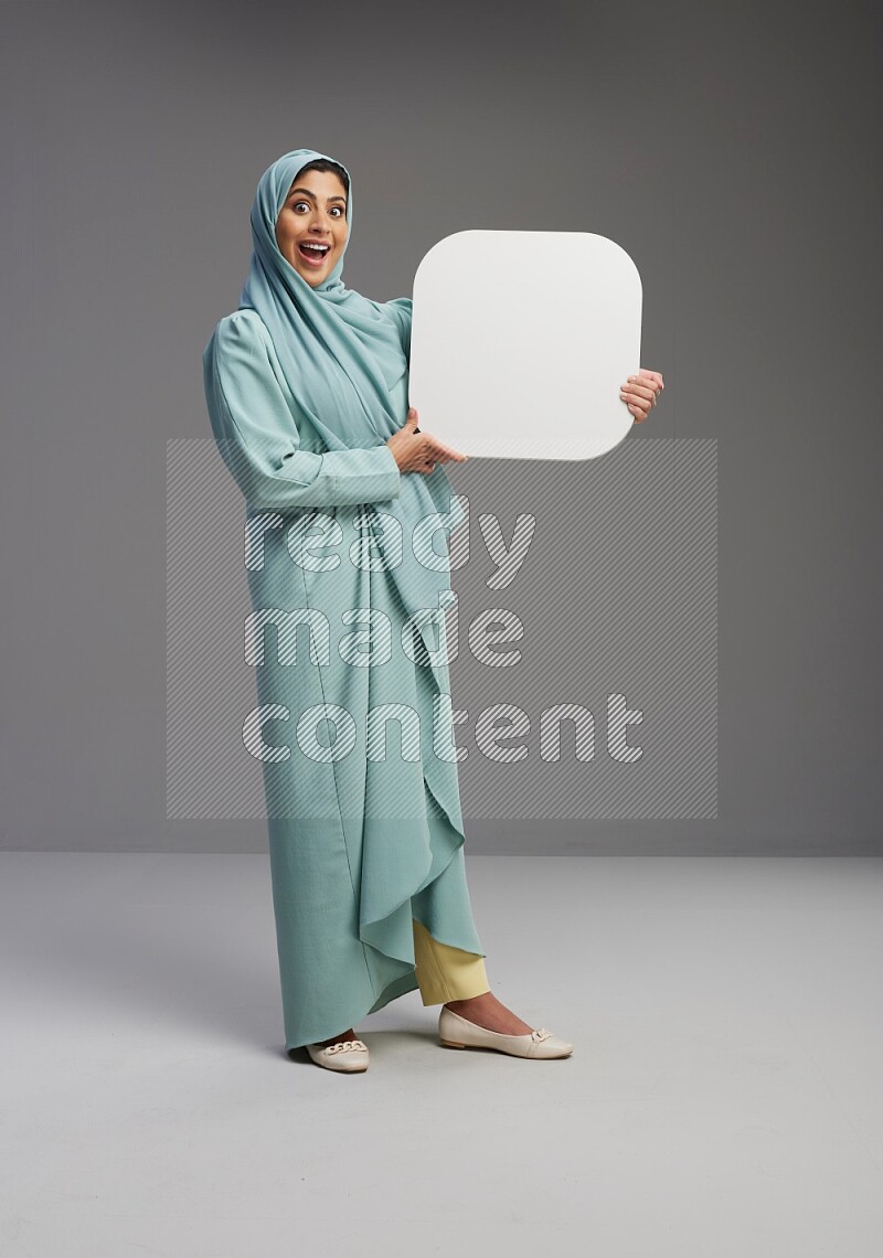 Saudi Woman wearing Abaya standing holding social media sign on Gray background