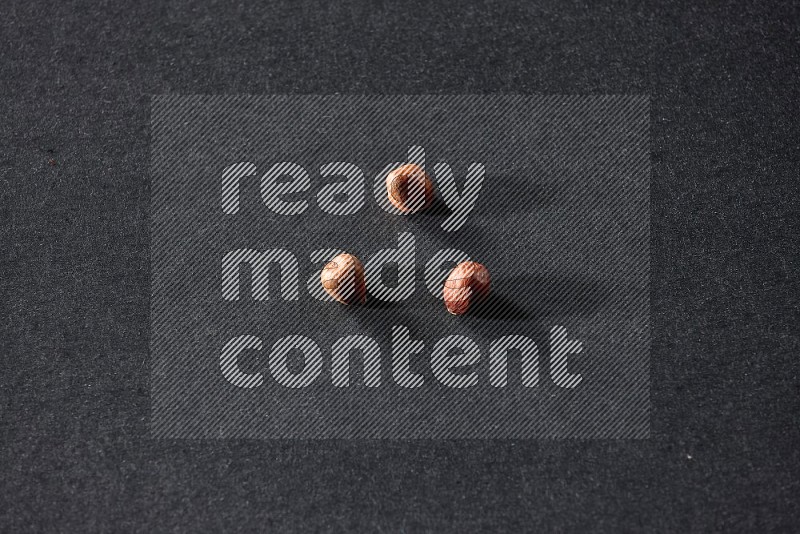 3 peeled hazelnuts on a black background in different angles